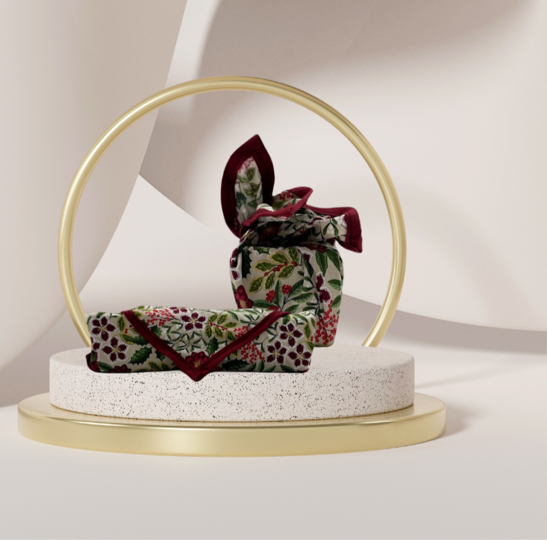 A fabric gift wrap with a festive floral design featuring crimson leaves and glistening berries against a grey background. Luxury, eco-friendly, embroidery personalisation