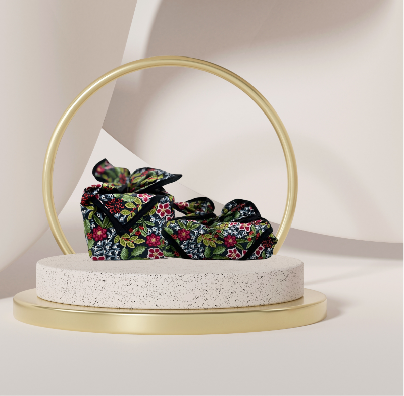 A fabric gift wrap with a floral pattern featuring crimson leaves, winter foliage, and blooming flowers. Luxury, eco-friendly, embroidery personalisation