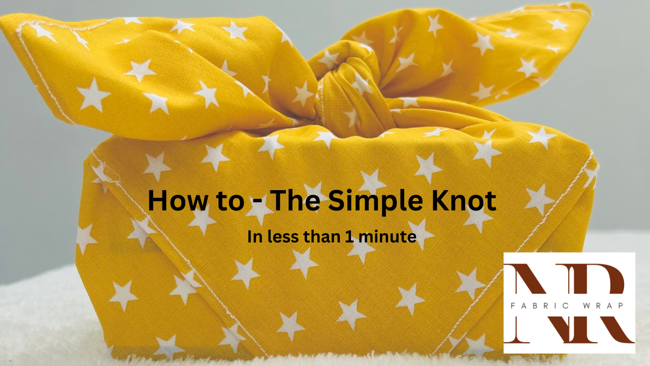 Load video: Step-by-step tutorial of a simple knot technique. Showing how to position a gift on a yellow star fabric wrap, fold the top and bottom corners, pull the sides tight, and finish with a secure double knot.