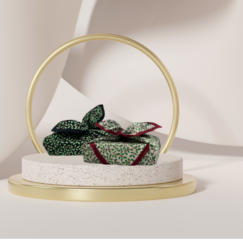 A luxury reusable fabric gift wrap with a holly pattern, featuring red berries and green leaves on a white background, eco friendly, personalised through embroidery 
Partnered with adorned by holly in midnight. 