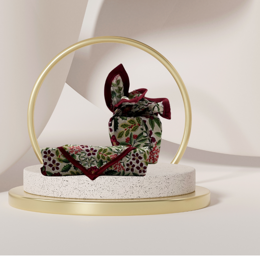 A fabric gift wrap with a festive floral design featuring crimson leaves and glistening berries against a grey background. Luxury, eco-friendly, embroidery personalisation 