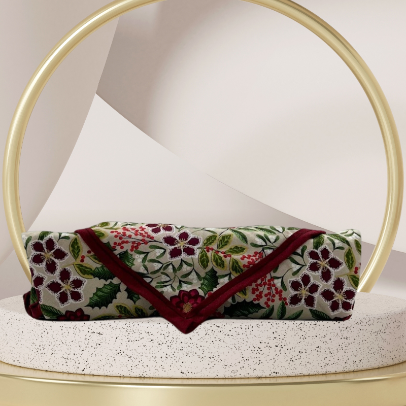 A fabric gift wrap with a festive floral design featuring crimson leaves and glistening berries against a grey background. Luxury, eco-friendly, embroidery personalisation 