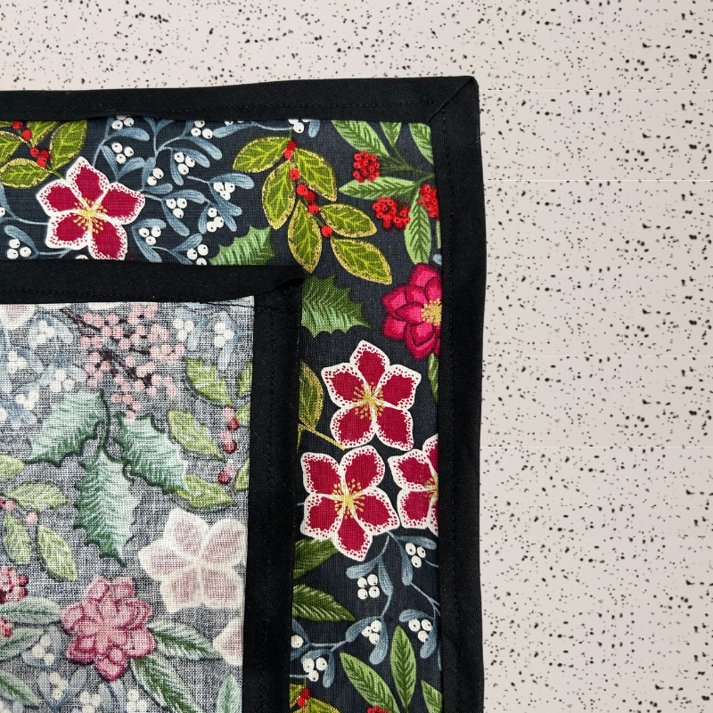 A fabric gift wrap with a floral pattern featuring crimson leaves, winter foliage, and blooming flowers. Luxury, eco-friendly, embroidery personalisation   