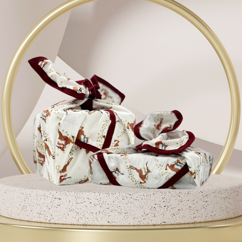 A reusable fabric gift wrap with a reindeer and snow design. Luxury, eco-friendly, embroidery personalisation 