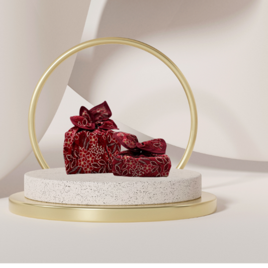 A fabric gift wrap with a Christmas-themed floral pattern, featuring red and green colours and gold accents. Luxury, eco-friendly, embroidery personalisation   