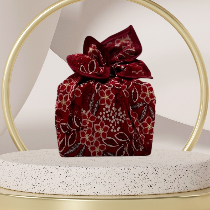 A fabric gift wrap with a Christmas-themed floral pattern, featuring red and green colours and gold accents. Luxury, eco-friendly, embroidery personalisation   