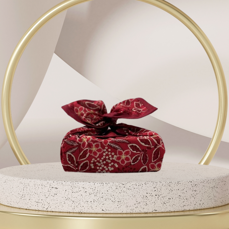 A fabric gift wrap with a Christmas-themed floral pattern, featuring red and green colours and gold accents. Luxury, eco-friendly, embroidery personalisation   